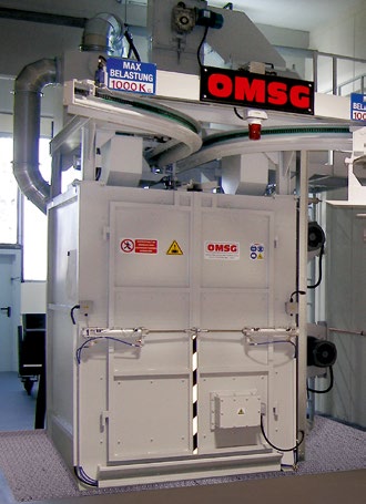 Eine Hängebahnstrahlanlage bei Hawle Freilassing mit Schleuderradturbine. Für das Aufrauen von Armaturen kommt Stahlguß-Strahlmittel zum Einsatz (kantig GH 16, 1,0 - 1,6 mm, Härte 60-64 HRC)